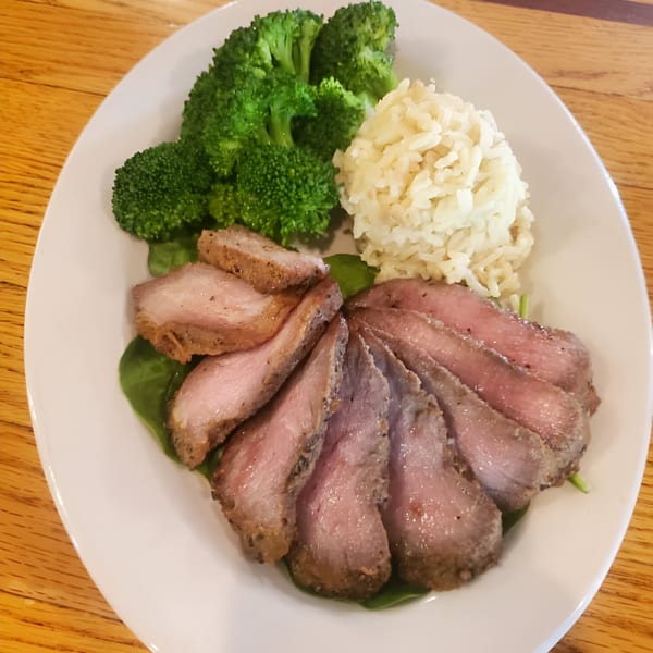 Sliced steak, broccoli, and rice on a white plate, served at Windham Restaurant.