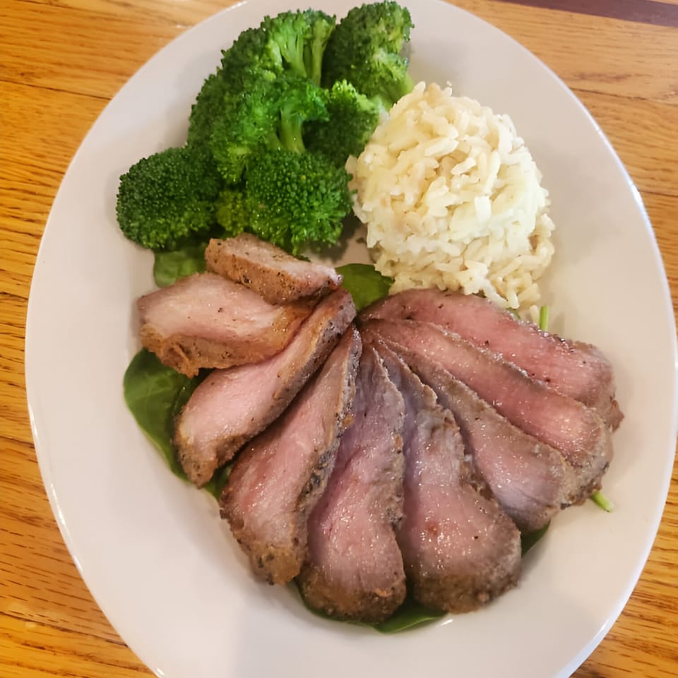 Sliced steak, broccoli, and rice on a white plate, served at Windham Restaurant.