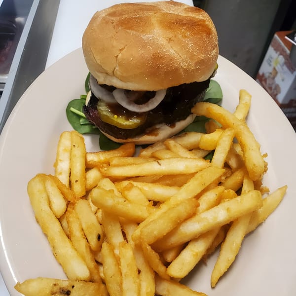 A Windham Restaurant burger with onions, pickles, and sauce, served with a side of golden fries.