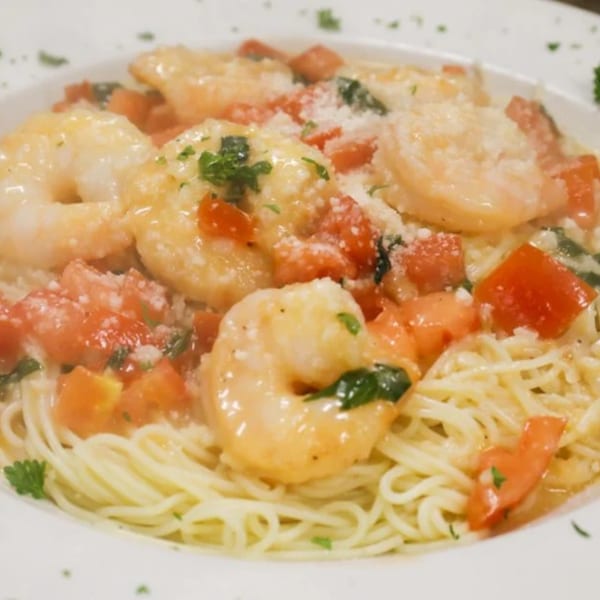 Shrimp scampi with angel hair pasta, diced tomatoes, and parsley, topped with grated cheese.