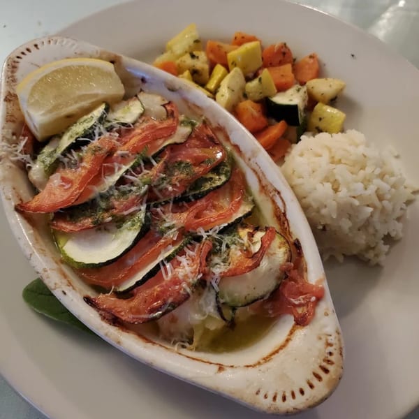 Baked zucchini and tomato gratin with parmesan, served with rice and mixed vegetables.